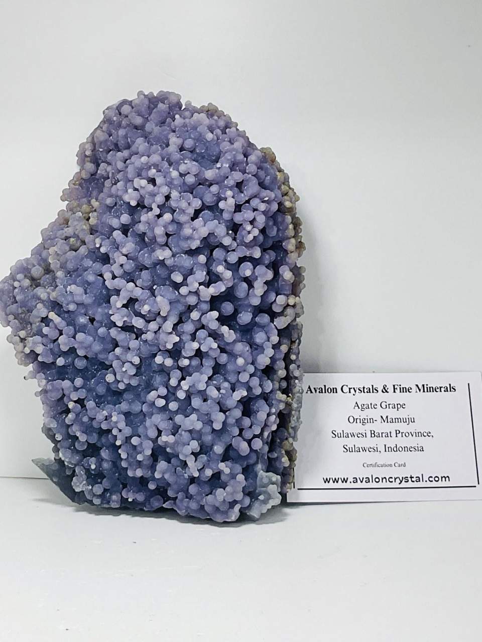 Rounded violet crystal specimen with an Avalon provenance card
