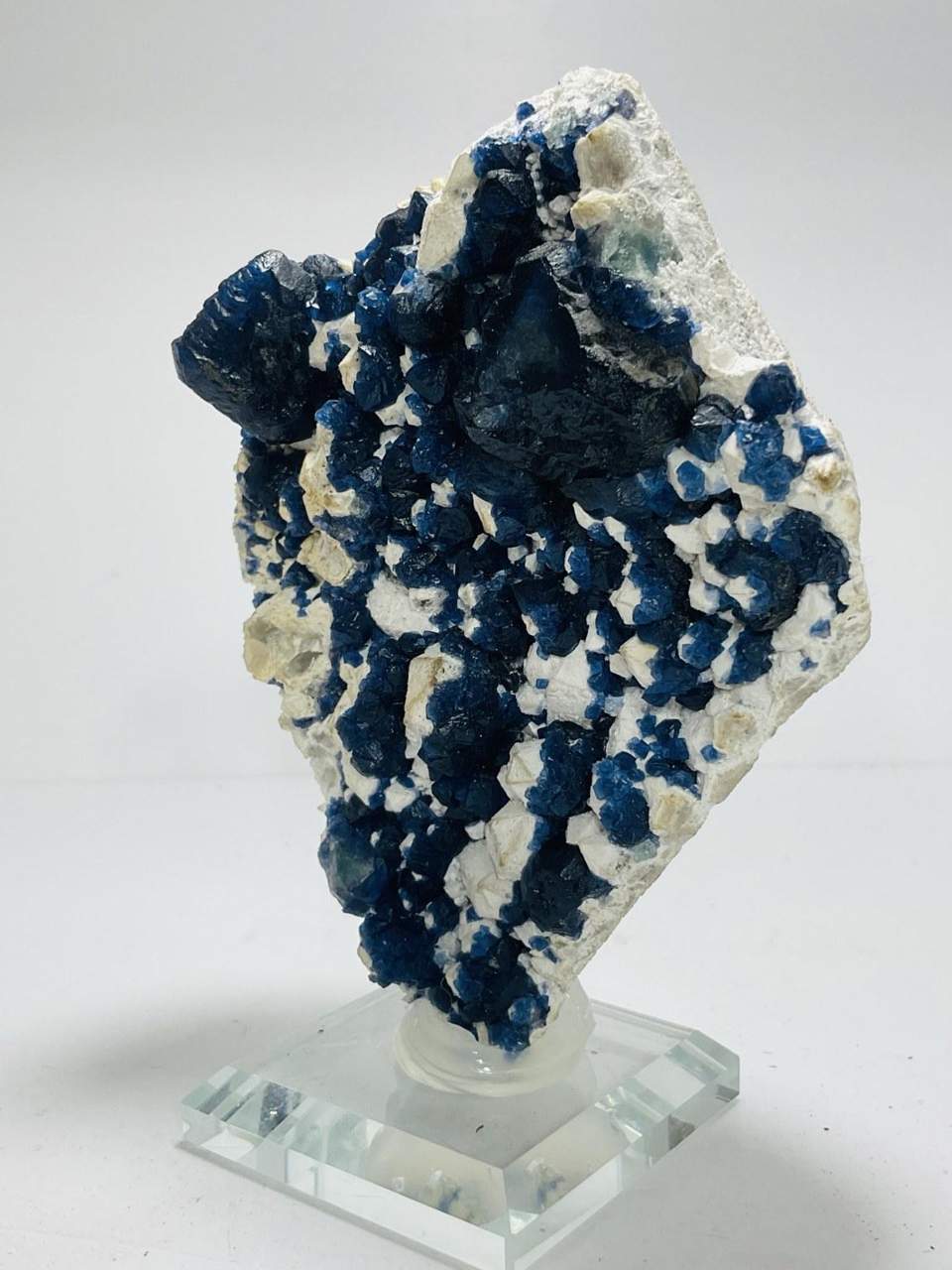 Deep blue mineral specimen displayed on a clear acrylic stand