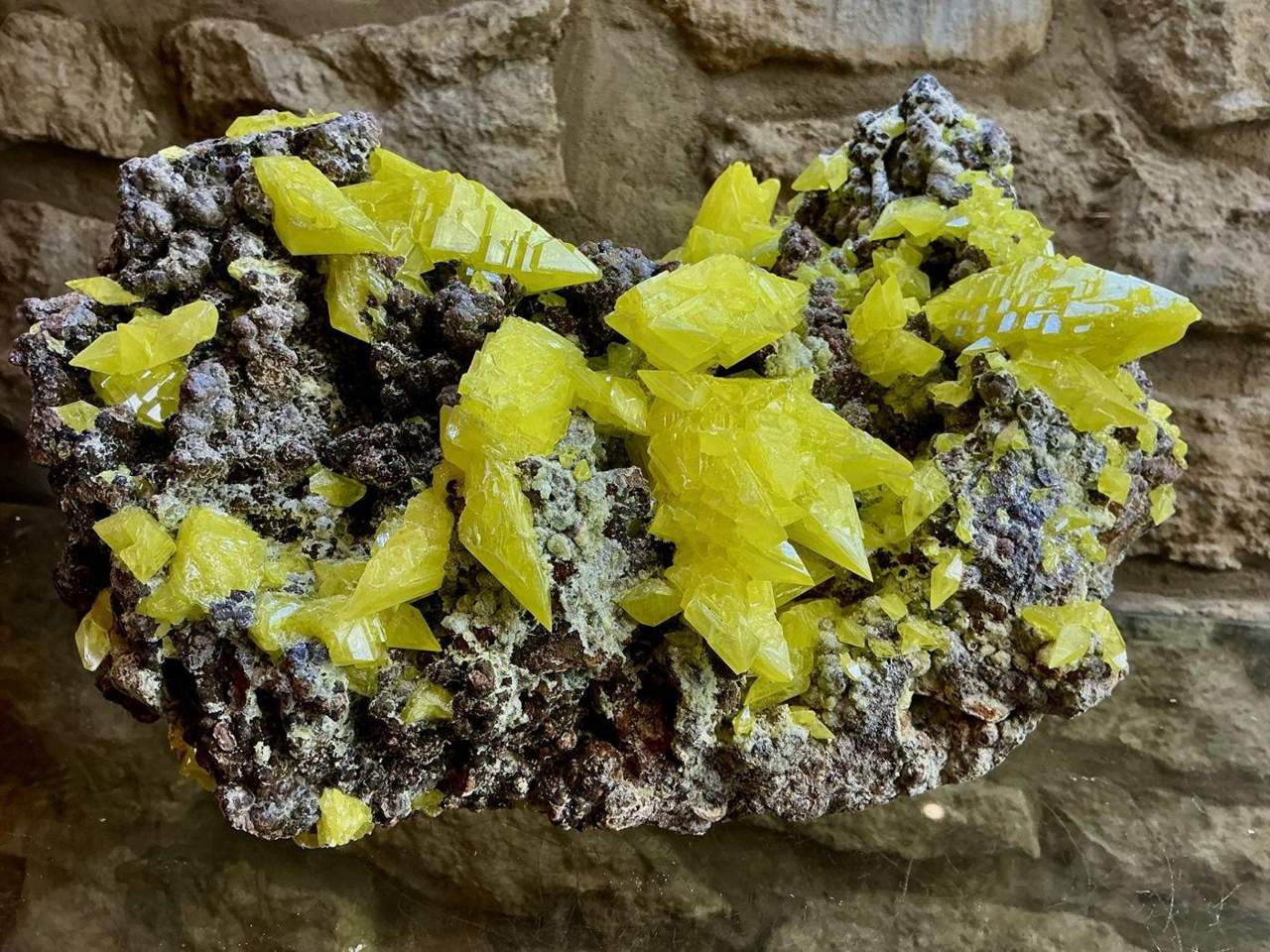 Bright yellow crystals across a dark mineral matrix