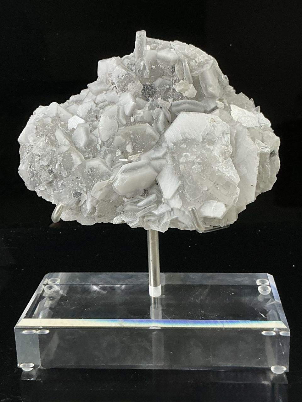 White tabular Liancheng Poker Chip Calcite on a clear display stand